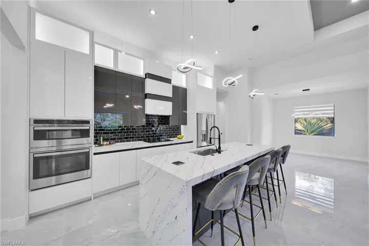 Kitchen with white cabinets, modern cabinets, hanging light fixtures, appliances with stainless steel finishes, and a breakfast bar