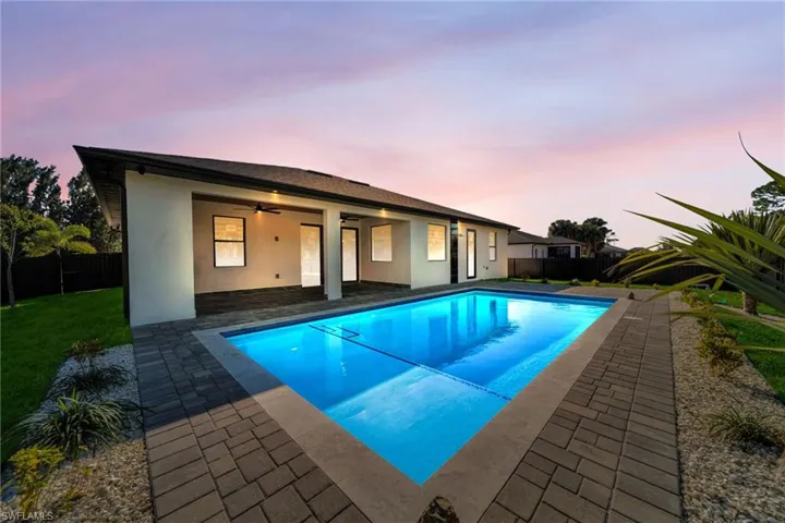 Back of house at dusk featuring ceiling fan, stucco siding, a patio, and a fenced backyard