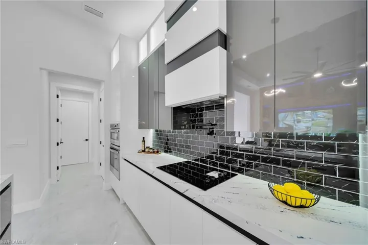 Kitchen featuring modern cabinets, a ceiling fan, black electric cooktop, and white cabinetry