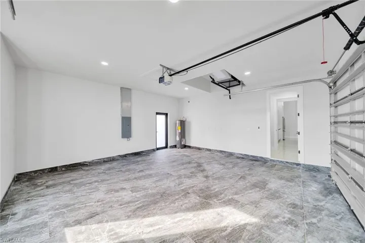 Garage featuring recessed lighting, electric panel, and electric water heater