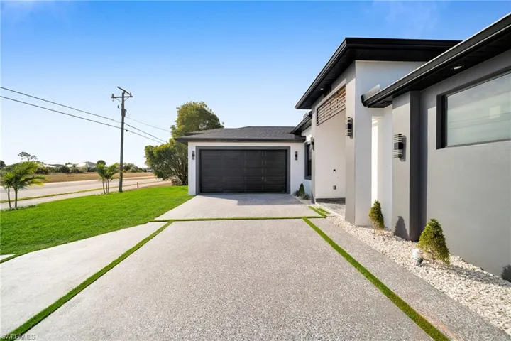 View of home's exterior featuring stucco siding, driveway, a lawn, and a garage