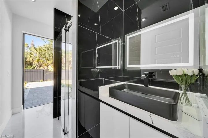 Bathroom with vanity, a shower with shower door, and backsplash