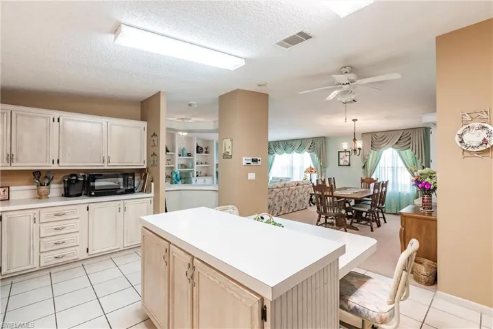 Kitchen with decorative light fixtures, a textured ceiling, light tile patterned floors, and a center island