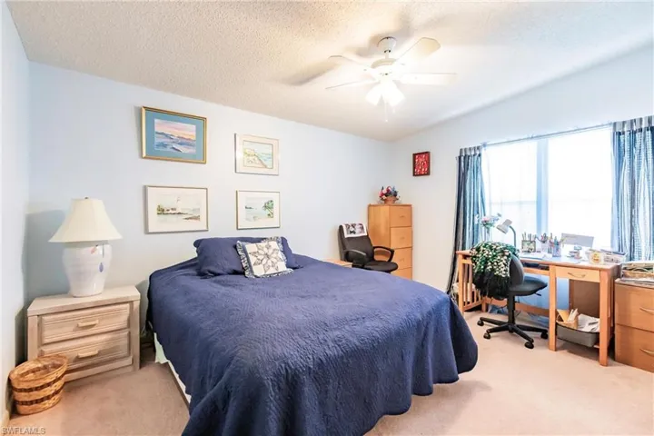 Carpeted bedroom with ceiling fan and a textured ceiling