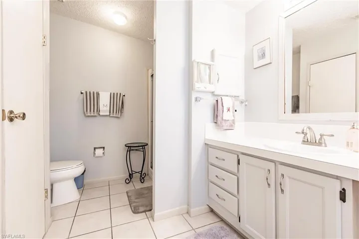 Bathroom featuring a textured ceiling, toilet, tile patterned flooring, and vanity