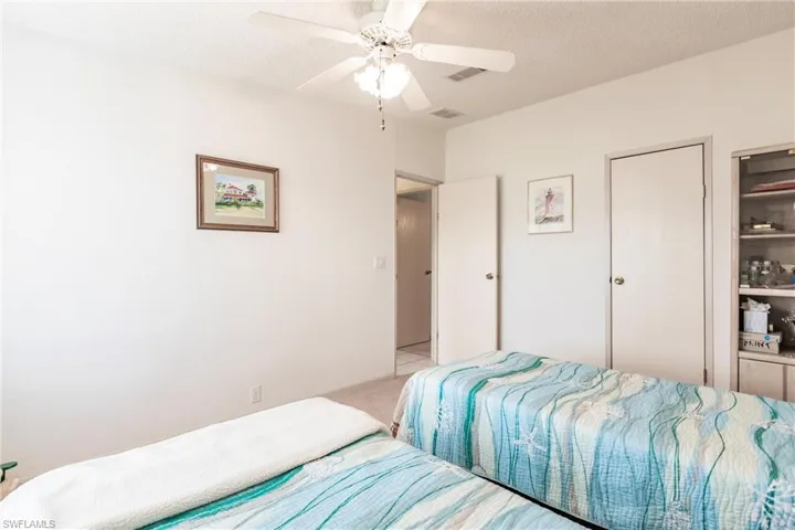 Bedroom with ceiling fan, a textured ceiling, and light carpet