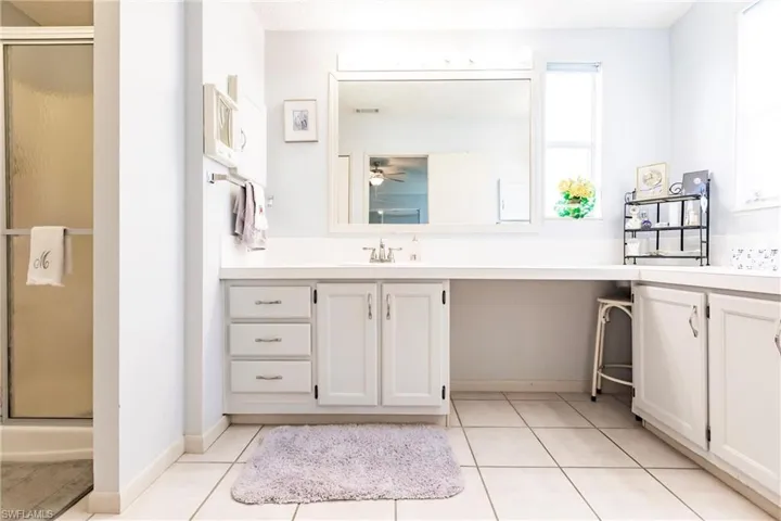 Bathroom with ceiling fan, vanity, tile patterned floors, and a shower with door