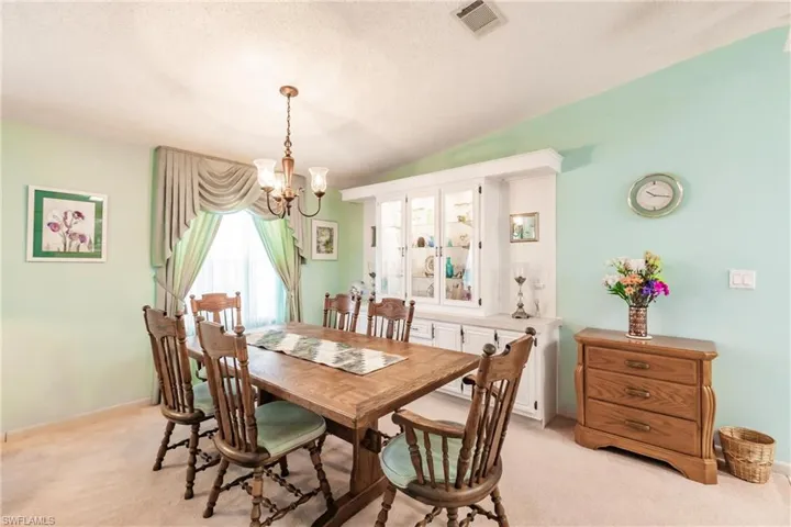Carpeted dining space with lofted ceiling, a chandelier, and a textured ceiling