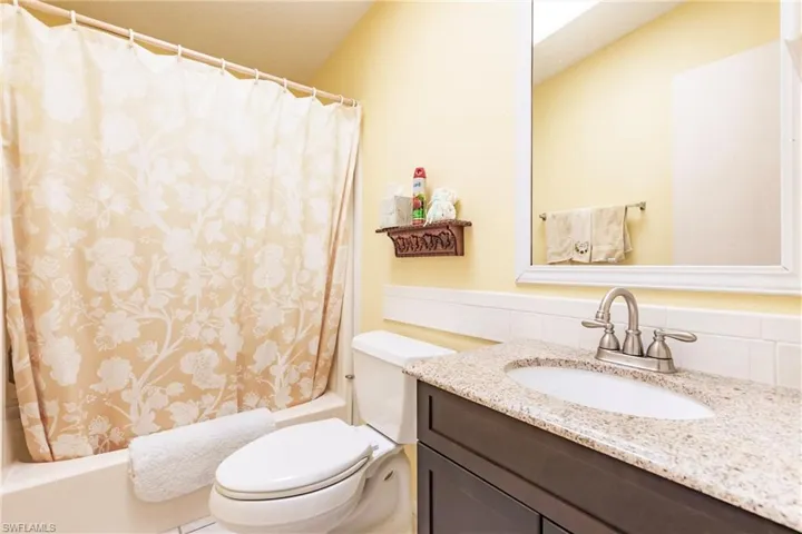 Full bathroom featuring toilet, shower / bath combination with curtain, backsplash, and vanity
