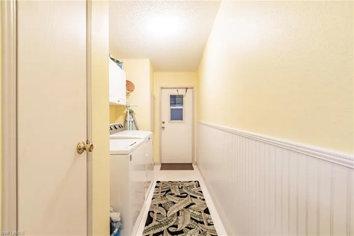 Clothes washing area with washer and dryer, cabinets, a textured ceiling, and tile patterned flooring