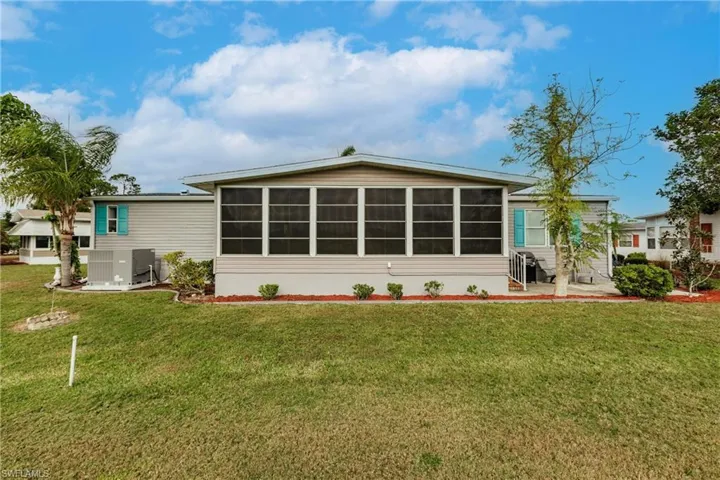 Back of house featuring a sunroom, a yard, and central AC unit