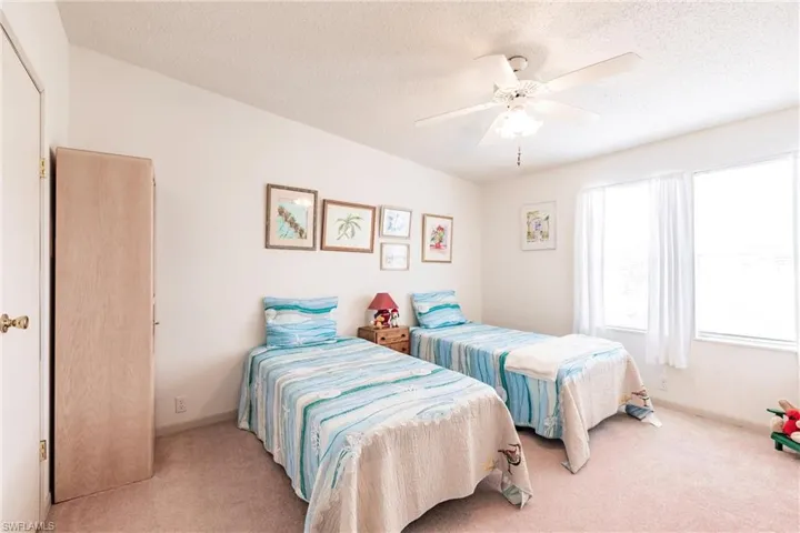 Carpeted bedroom featuring ceiling fan and a textured ceiling