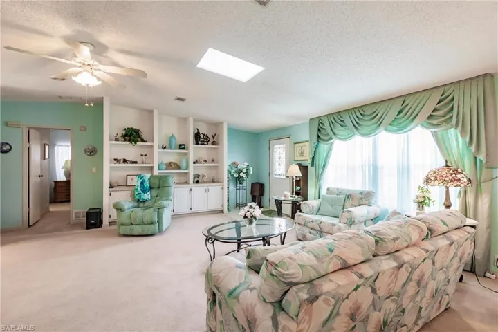 Living room featuring a textured ceiling, light carpet, and a skylight