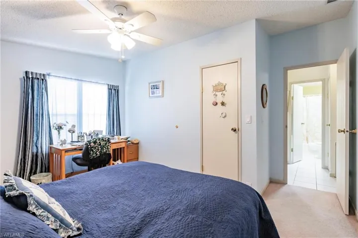 Bedroom with light carpet, ceiling fan, and a textured ceiling