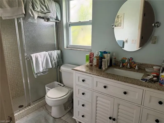 Full bathroom with vanity, a shower stall, and tile patterned flooring