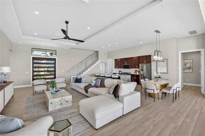 Living room featuring a chandelier, light wood finished floors, stairs, recessed lighting, and a ceiling fan
