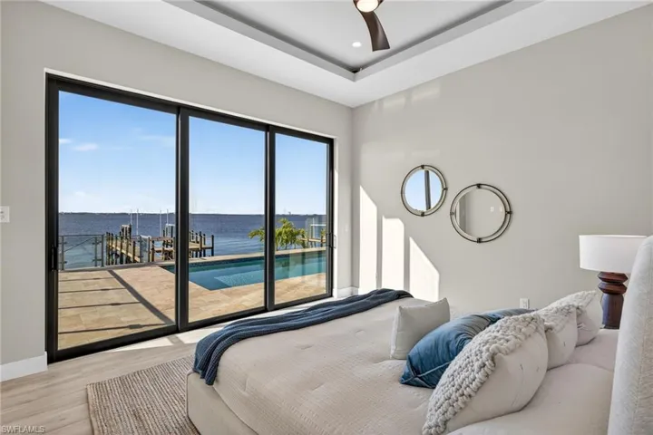 Bedroom featuring a water view, access to outside, wood finished floors, a ceiling fan, and recessed lighting