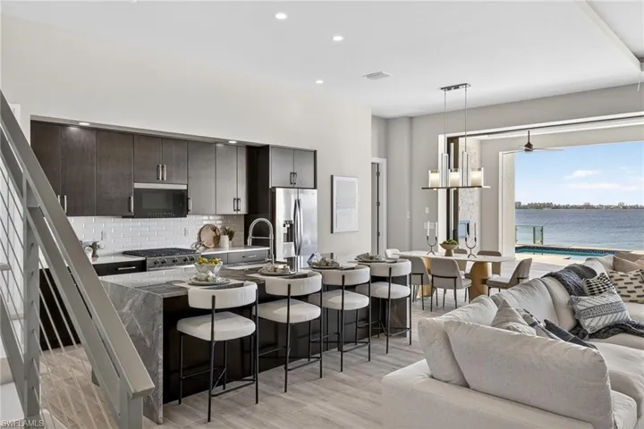 Kitchen featuring a kitchen bar, a center island with sink, hanging light fixtures, stainless steel appliances, and recessed lighting