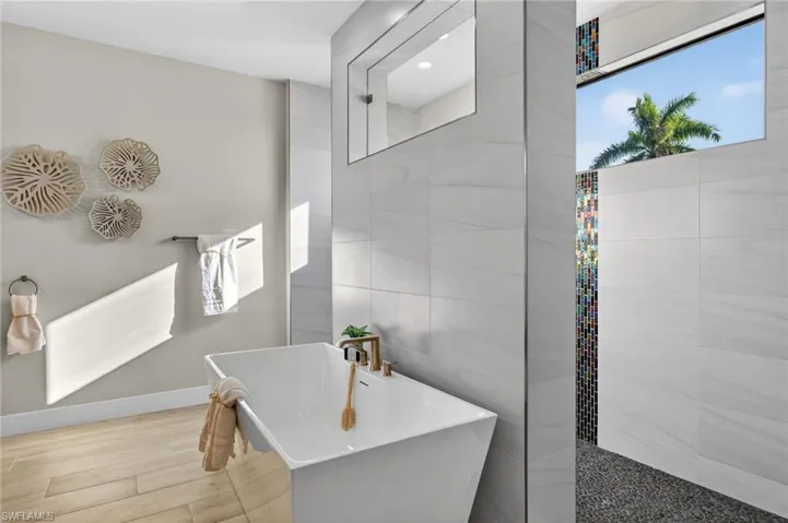 Bathroom with a soaking tub, wood finish floors, and tile walls