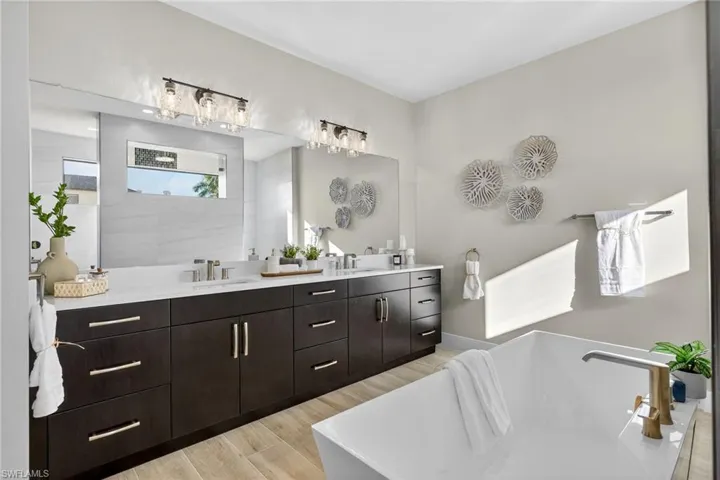 Full bathroom with a soaking tub, double vanity, and light wood-type flooring