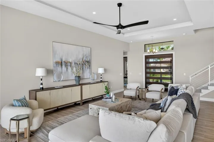 Living room featuring wood finished floors, recessed lighting, ceiling fan, stairs, and a raised ceiling