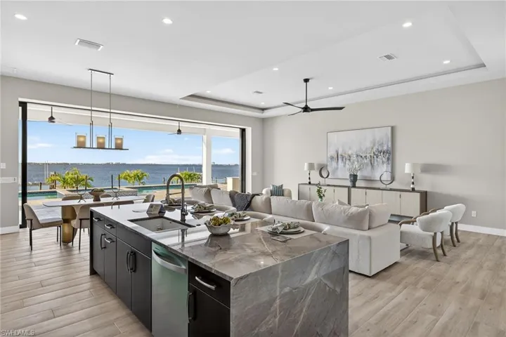 Kitchen featuring dark cabinetry, modern cabinets, a water view, an island with sink, and a ceiling fan