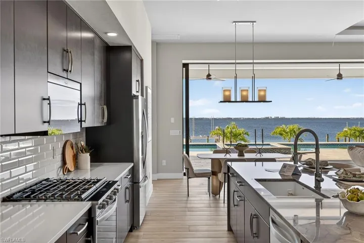 Kitchen featuring appliances with stainless steel finishes, pendant lighting, wood tiled floors, a water view, and tasteful backsplash