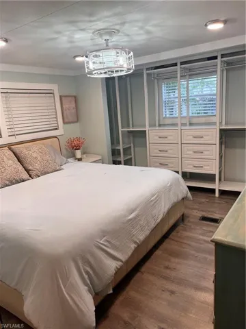 Master bedroom featuring, laminate floors and decorative light and ceiling fan combo, built-in closet space