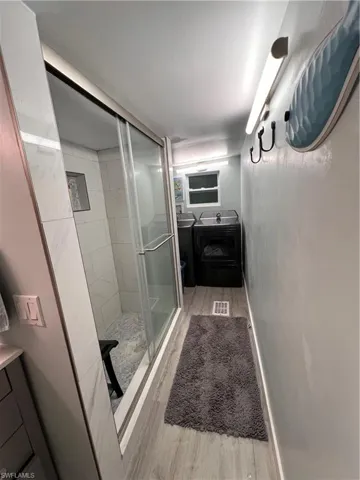 Guest bathroom with vanity, a shower stall, and laminate flooring.  Laundry in guest bathroom area.