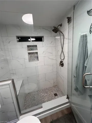 Full master bathroom featuring a large stall shower and laminate floors