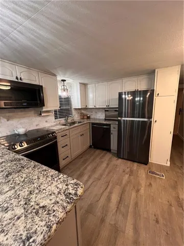 Kitchen featuring stove, fridge, dishwasher, microwave, granite countertops and laminate flooring.