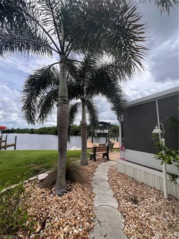 View of property's side yard featuring a water view, and partial view of attached screen porch