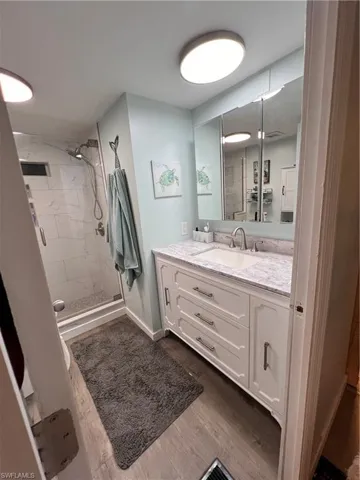 Full master bathroom featuring a shower stall, vanity, and laminate floors