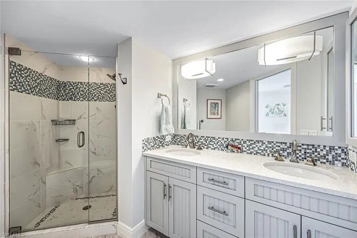 Bathroom with decorative backsplash, a marble finish shower, double vanity, and a wall unit AC