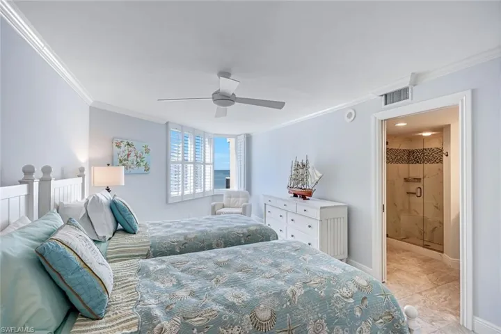Bedroom featuring crown molding, a ceiling fan, light tile patterned floors, and ensuite bath