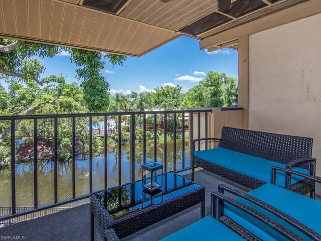 The balcony provides views of a body of water with lush trees and foliage in the background