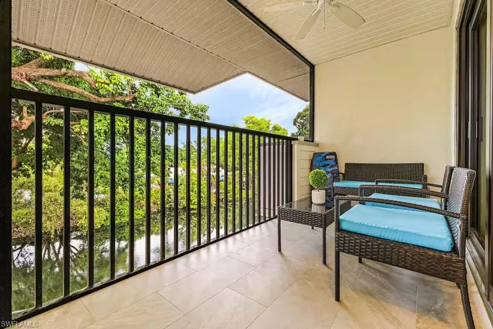 The balcony features a tiled floor, a black metal railing, and a ceiling fan