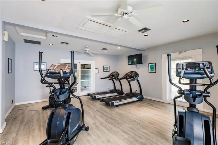 This fitness area features light gray walls, recessed lighting, and ceiling fans