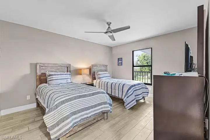Bedroom featuring light-colored walls, wood-look tiled flooring, and a ceiling fan