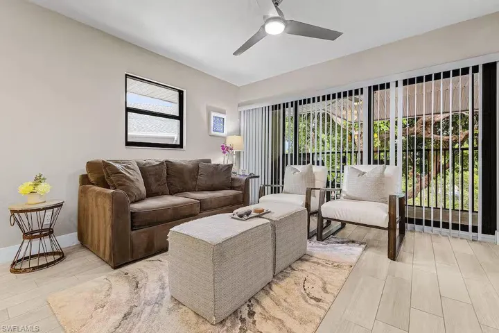 The living area features light-colored flooring, a large window, and sliding glass doors with vertical blinds