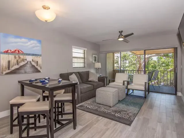 The living area features light-toned flooring, a ceiling fan, and sliding glass doors that open to an outdoor space