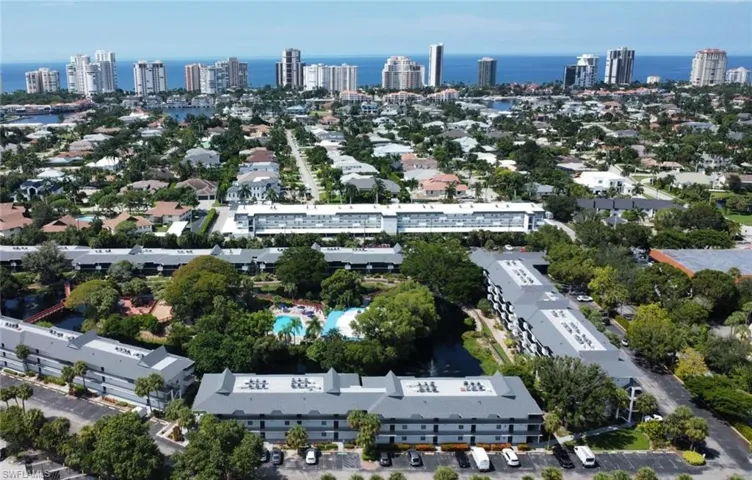 Aerial view of the property, featuring a swimming pool, surrounding green spaces, and a body of water