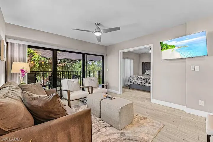 Living area featuring a ceiling fan, light-toned flooring, and a sliding glass door opening to a balcony