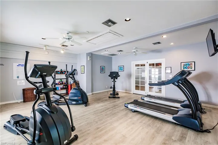 The property features an exercise room with wood-style flooring, white ceiling fans, and recessed lighting
