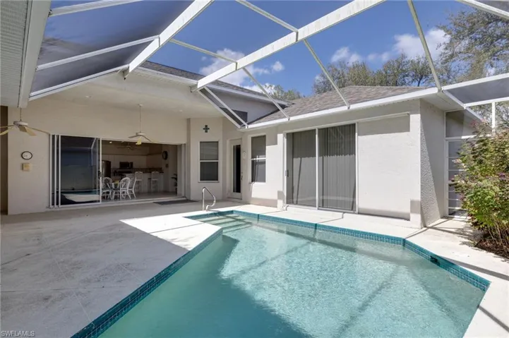 Back of property with a sunroom, an outdoor pool, a patio area, and stucco siding