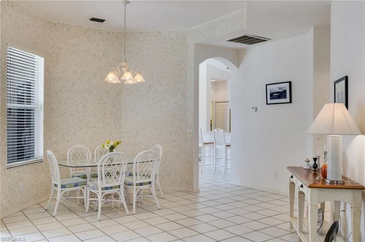 Dining space featuring arched walkways, wallpapered walls, hanging lights, and light tile patterned floors