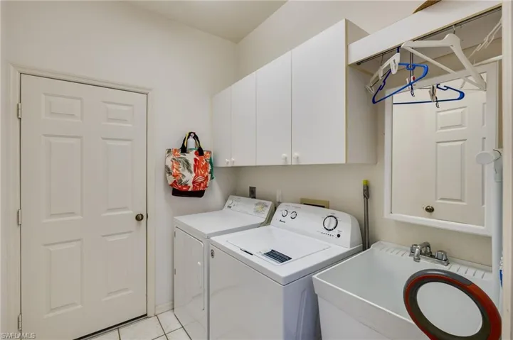 Laundry room with cabinet space, separate washer and dryer, and light tile patterned flooring