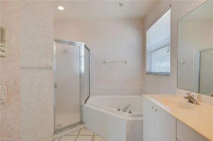 Full bath with vanity, a garden tub, a shower stall, and light tile patterned flooring