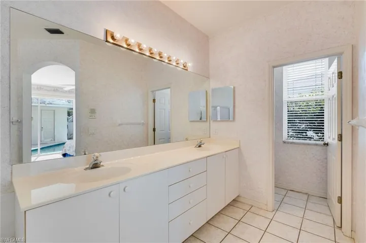 Ensuite bathroom featuring double vanity and light tile patterned floors