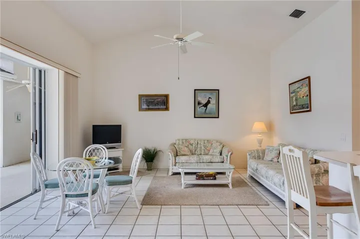 Living room with lofted ceiling, a ceiling fan, and light tile patterned flooring